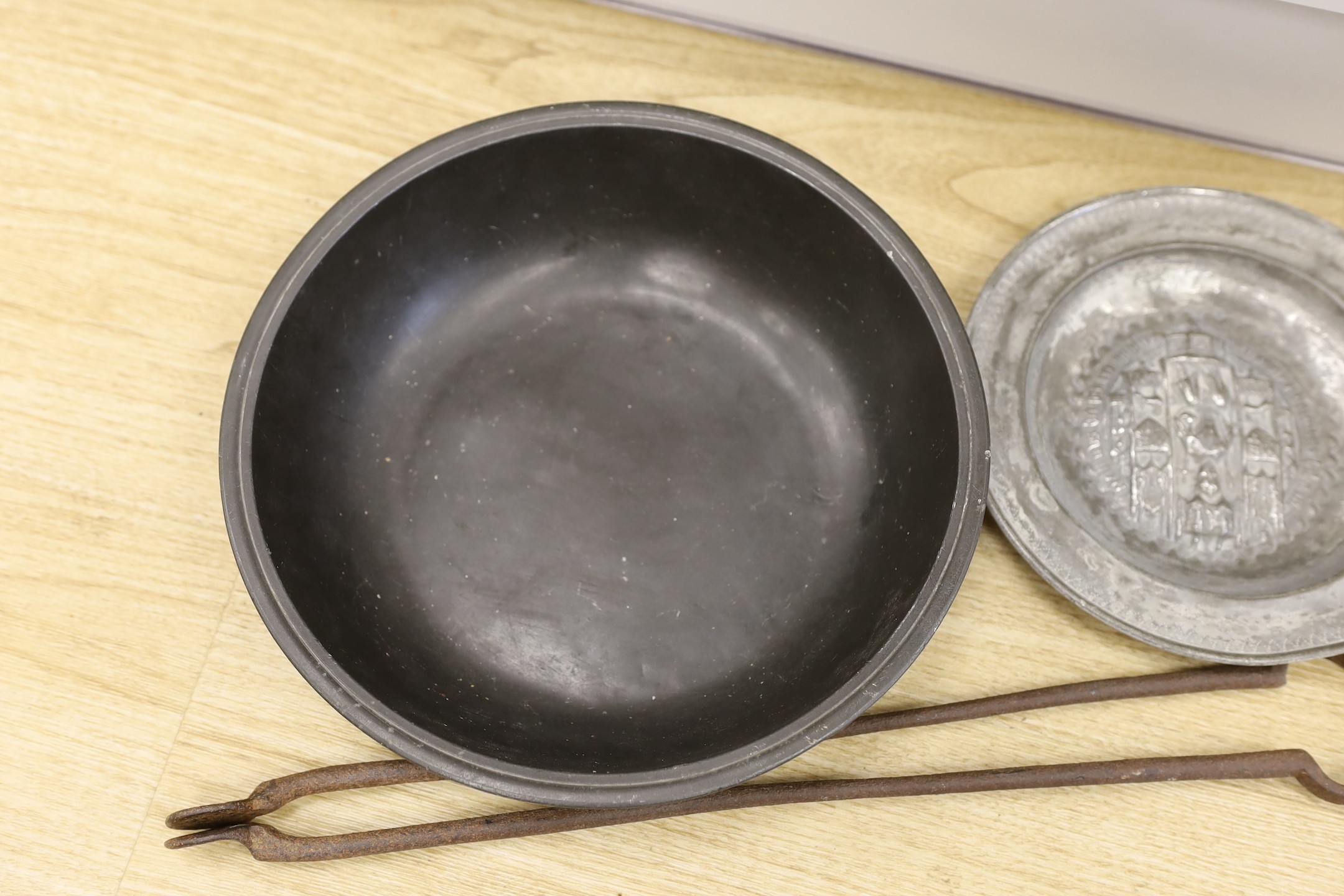 An 18th century pewter dish, an embossed pewter plate and a pair of iron fire tongs